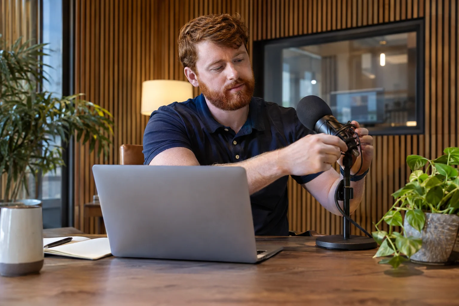 Professional adjusting a microphone at his workstation.