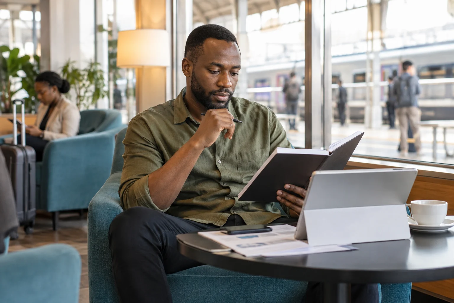 A professional checking a document notebook in a bright station lounge